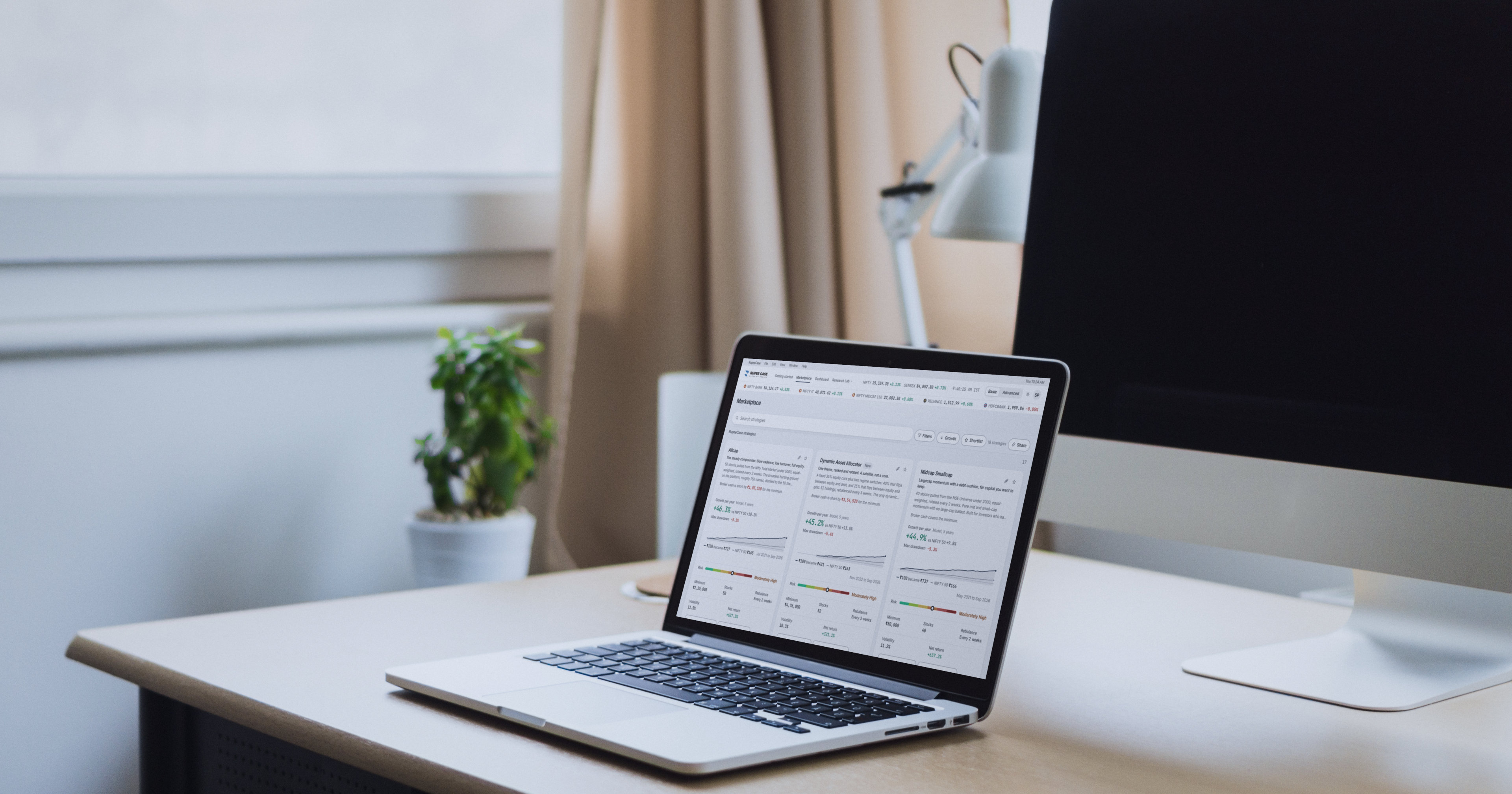 A laptop on a bright desk by a window showing the RupeeCase marketplace in light theme