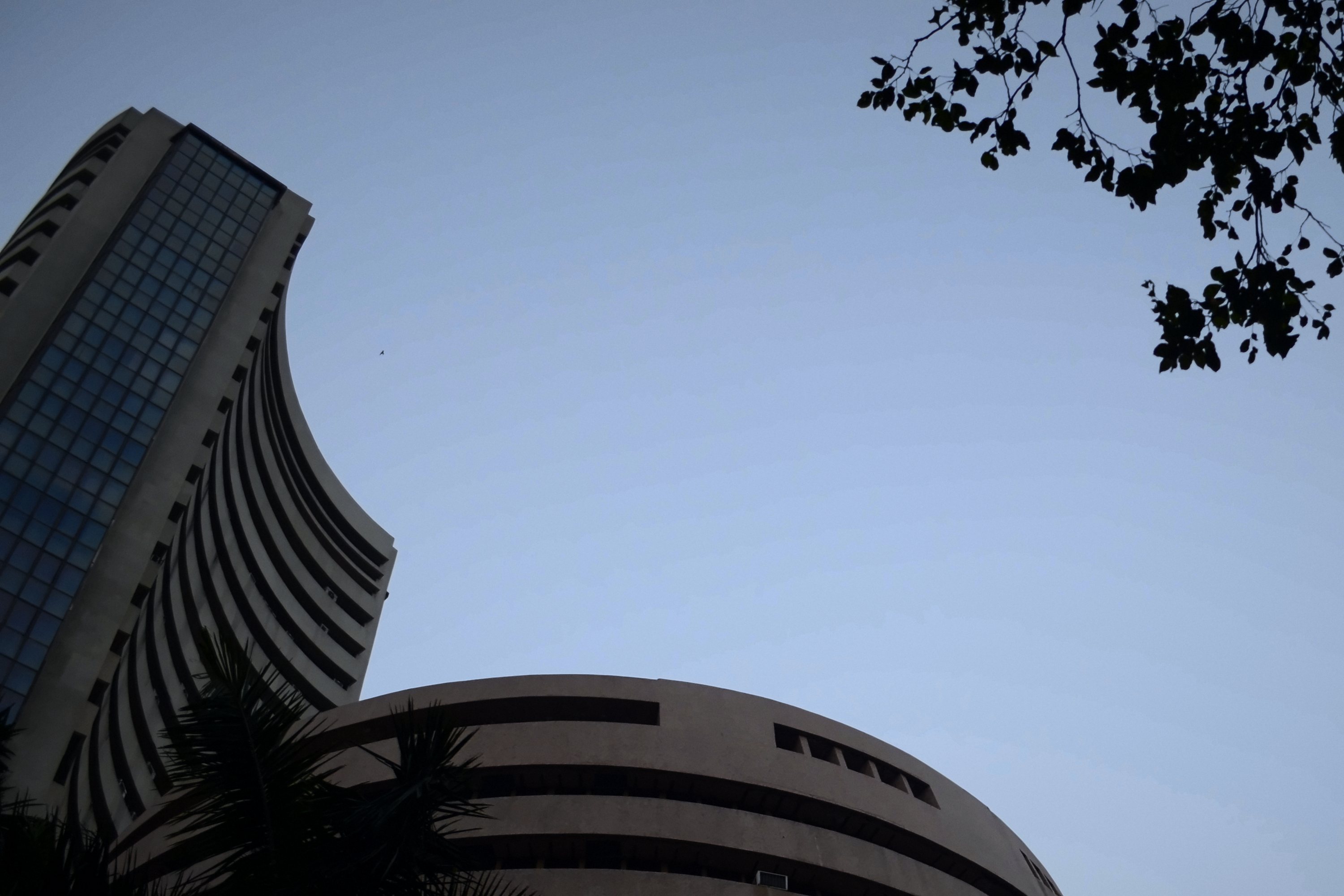 Phiroze Jeejeebhoy Towers and the BSE rotunda on Dalal Street at dusk, palms in silhouette